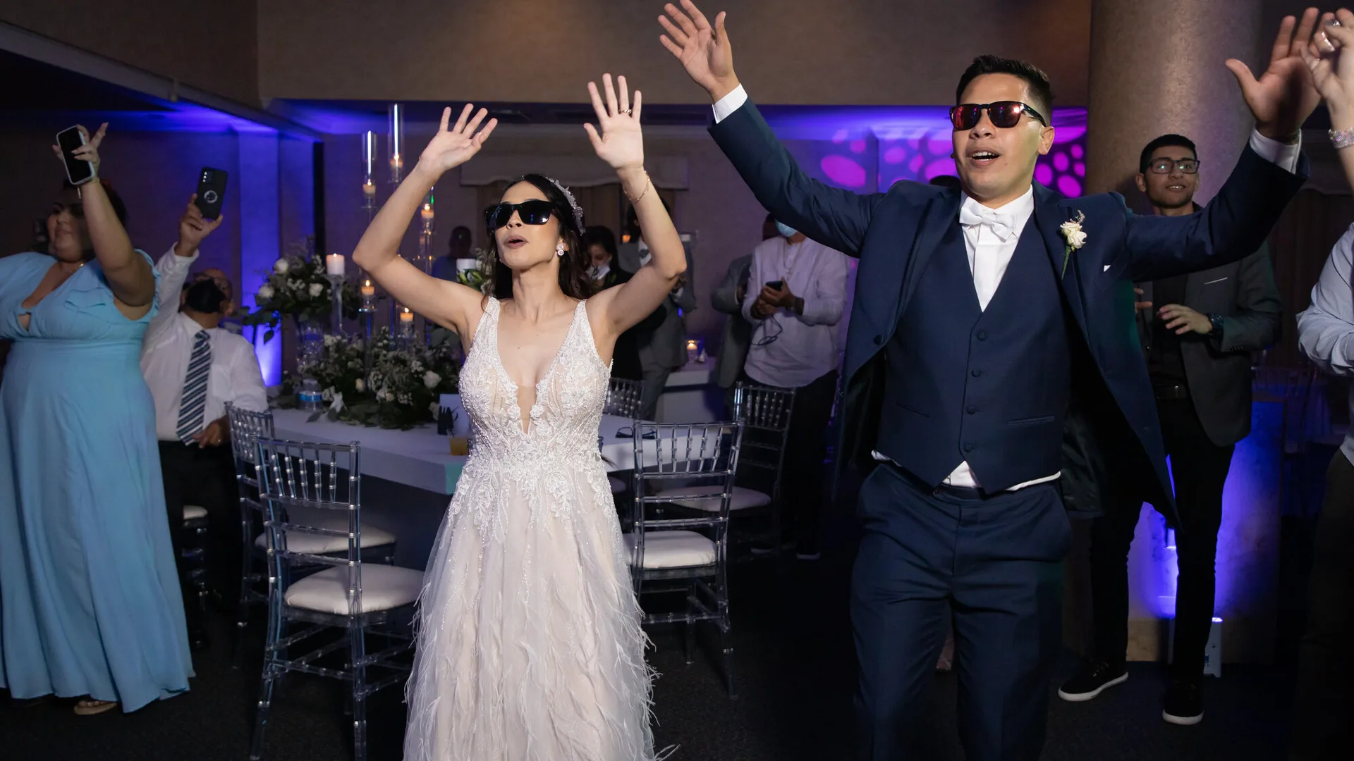 Couple in sunglasses dancing with guests at their reception