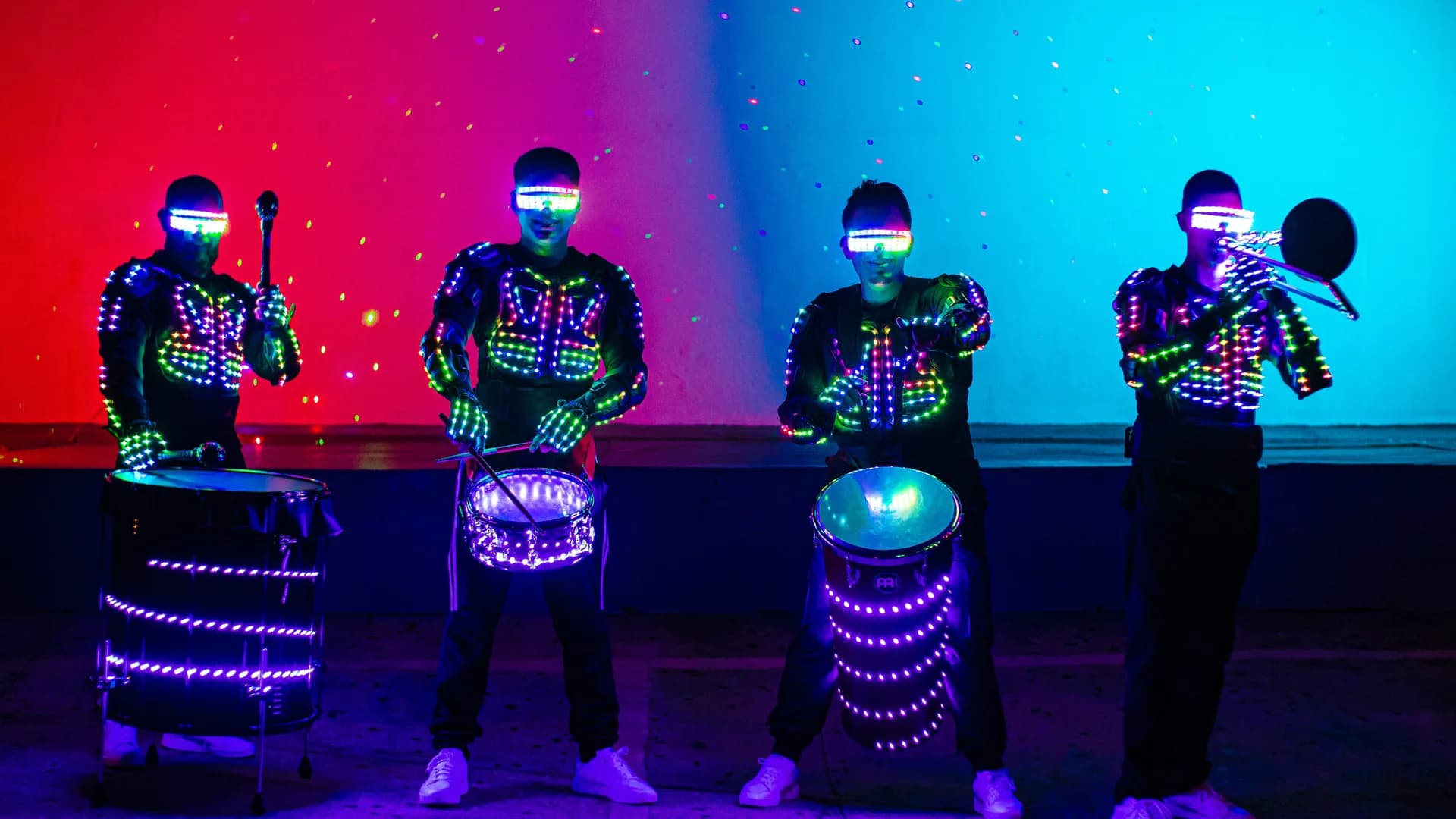 Four LED batucada musicians with illuminated costumes and drums