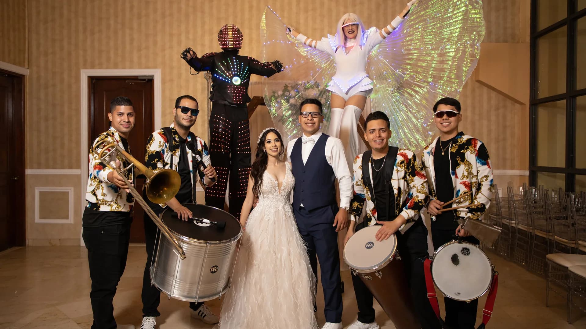 Novia con músicos de batucada, un robot LED y una zanquera con alas de luz