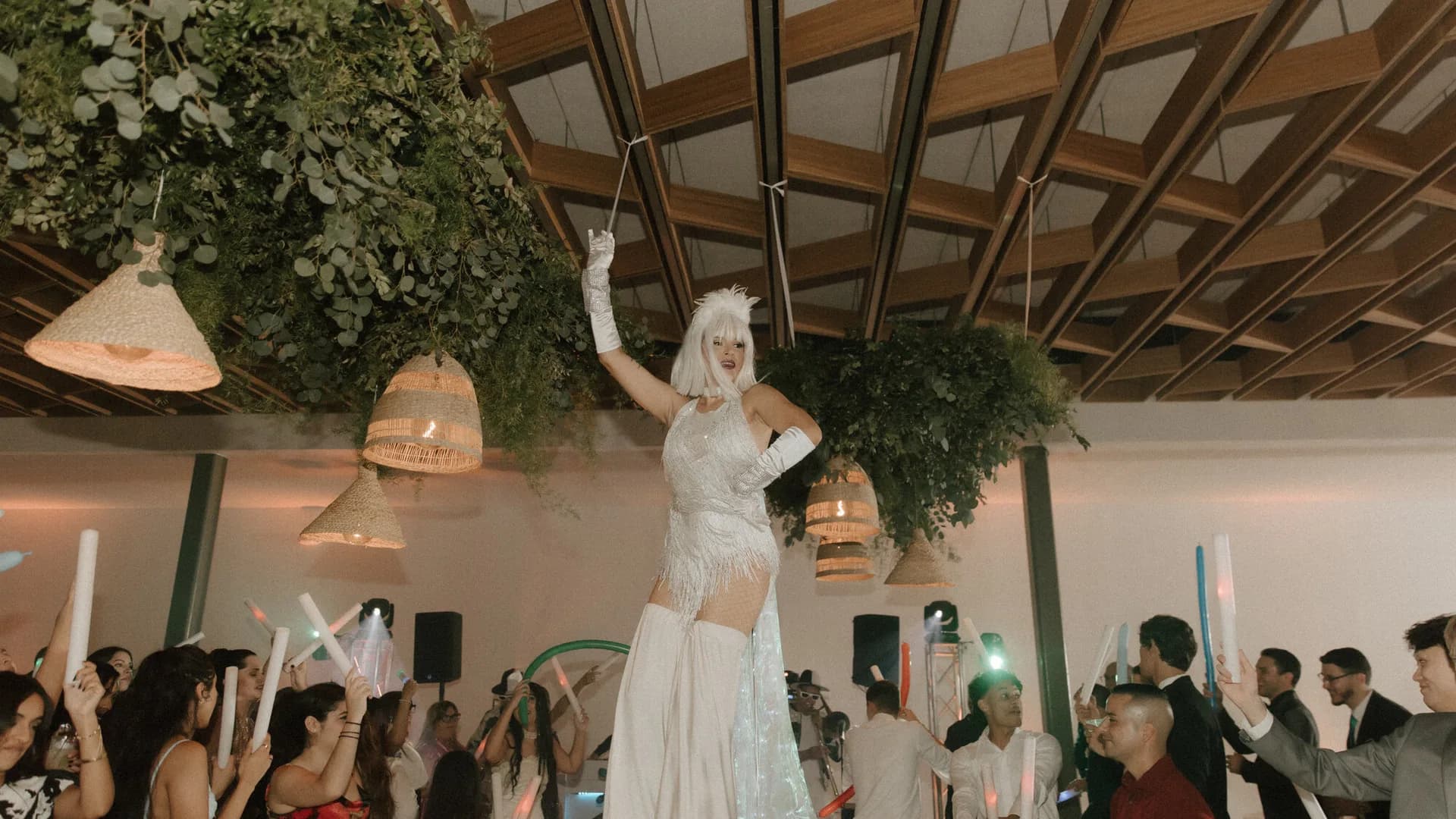 Zanquera con vestuario blanco sobre invitados que bailan