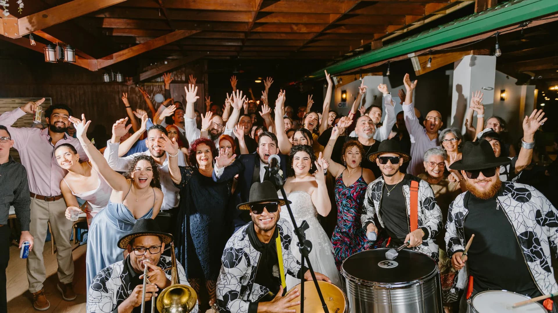 Invitados con los brazos en alto junto a músicos de batucada
