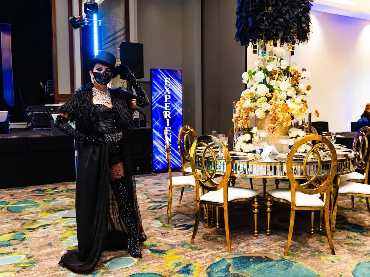Personaje gótico estilo años 20 con sombrero de copa y capa negra junto a una mesa de gala