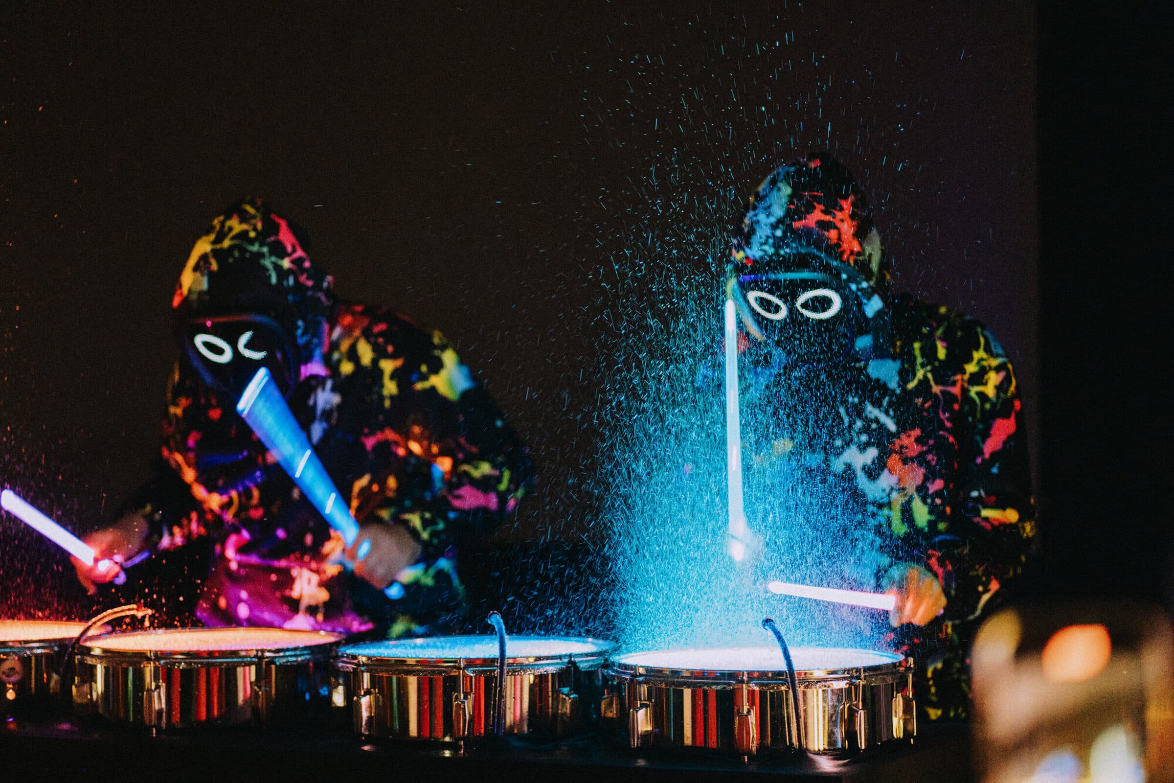 Splash Drummers tocando tambores con agua que salpica bajo luces de colores