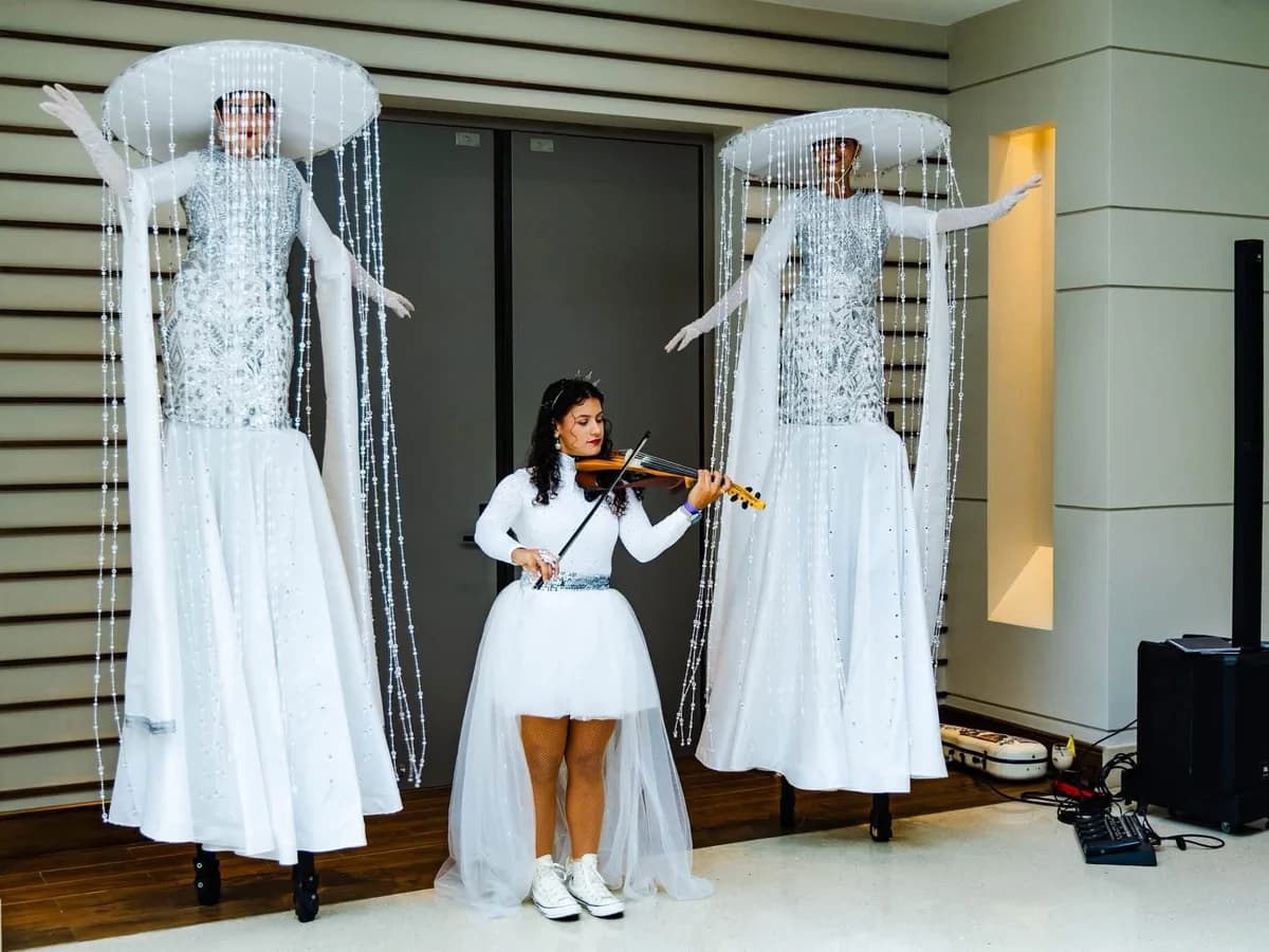 Dos zanqueras temáticas de blanco con violinista en vivo