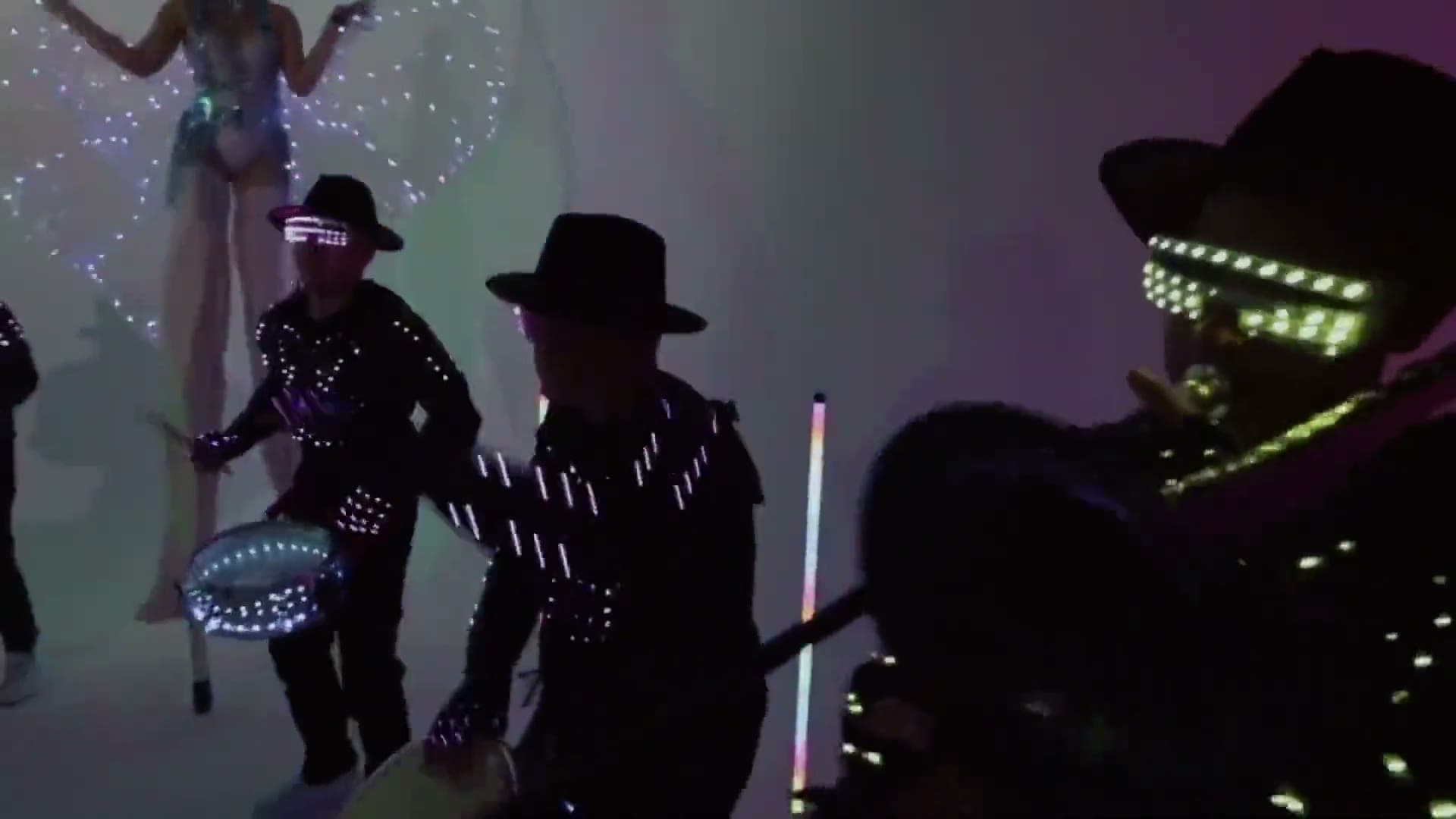 Percusionistas con sombreros y trajes LED en un show en vivo